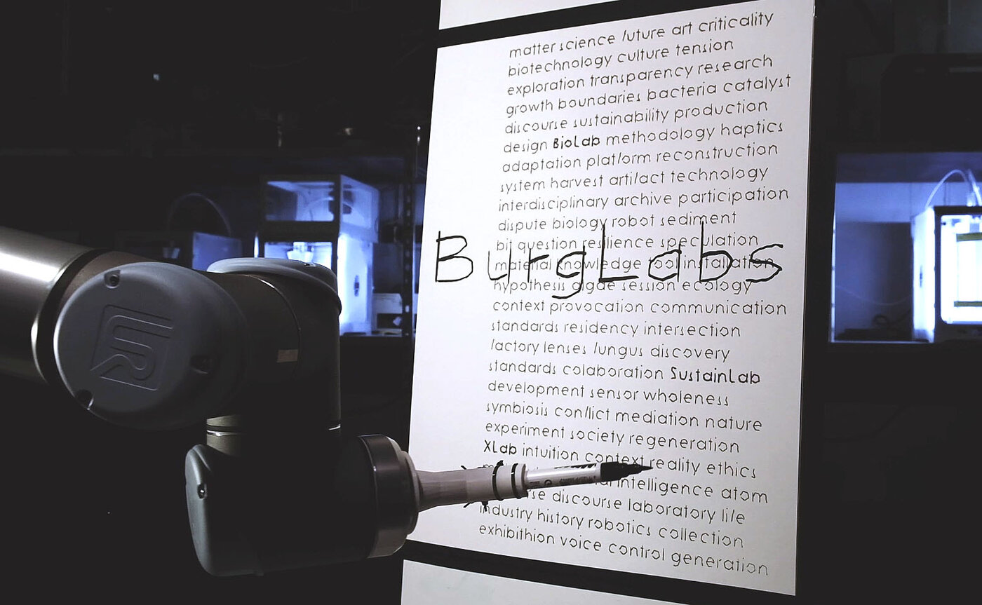 Roboterarm mit montiertem Pinsel produziert ein Poster mit der Aufschrift BurgLabs - Foto Simon Maris
