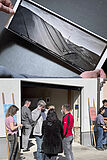Montage von 2 Bildern: Hände zeigen einem Schwarz Weiss Landschaftsbild und Menschen stehen vor einem Eingang